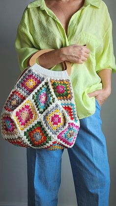 a woman holding a crocheted purse in her hands