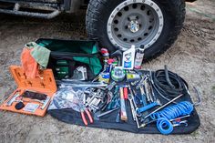 an assortment of tools sitting on the ground next to a truck