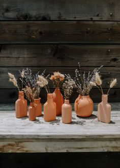 five vases with dried flowers in them sitting on a table