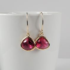 "Garnet glass earrings, a timeless classic perfect for any occasion. Beautiful deep red glass earrings feature faceted glass drops (15mm) framed in 16k gold dangling from almond-shaped ear wires hand forged in 14k Gold Fill with tumbled and polished ends for comfort. Dainty earrings measure 1 3/4 inches from top to bottom and the faceted glass drop is 1/2 inch wide. Silicone backs included. In the January birthstone, these artisan earrings make a great gift for women; sister gift, birthday gift Elegant Hypoallergenic Glass Earrings, Elegant Glass Crystal Drop Earrings, Glass Drop Crystal Earrings For Gift, Elegant Glass Earrings For Gift, Elegant Crystal Glass Earrings For Gifts, Elegant Glass Crystal Earrings For Gift, Sister Birthday Gift, January Birthstone Jewelry, Great Gifts For Women