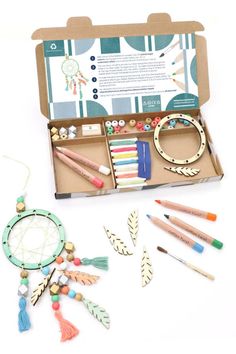 an open box filled with lots of crafting supplies and beads on top of a white surface