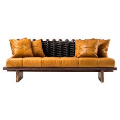 a brown leather couch sitting on top of a wooden table next to two black pillows