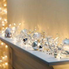 white and silver ornaments are sitting on the mantle