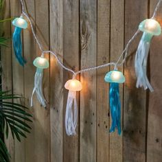 a string of lights that have jellyfishs on them hanging from a wooden fence