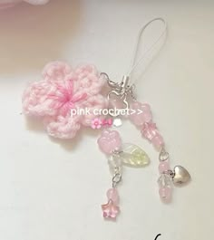 pink crocheted flower and charms on a white surface with the words pink crochet written below it