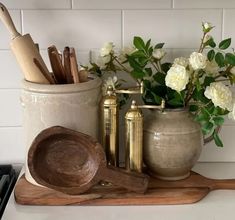 kitchen utensils and wooden spoons are sitting on a counter next to flowers