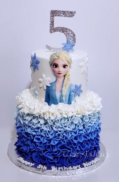 a birthday cake decorated with blue and white ruffles, the number five is 5