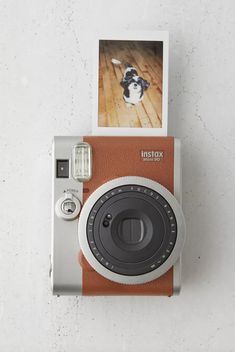 an orange and white polaroid camera sitting on top of a wooden floor