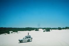 a person standing on top of a truck in the sand