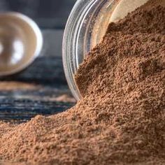 a jar filled with brown powder next to a spoon