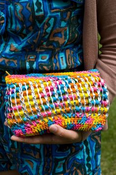 a woman holding a colorful purse in her hands