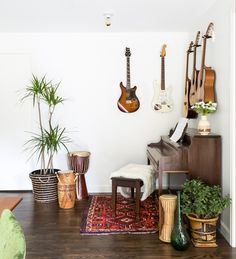 a living room filled with lots of furniture and guitars hanging on the wall next to a piano