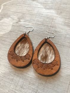 I'm so excited to bring y'all these hand tooled, genuine  leather cutout earrings, layered over hair on cowhide . These are chic- meets-western! Each pair is made to order, so pattern variations will occur, but your pair will be very similar to the photos. Finished with sterling silver-plated ear wires. Earring backs are natural gray suede. Approximate length, 3". Thanks for shopping @boholeathercraft ! Follow me on Instagram & Facebook for sneak peaks, updates, and the occasional promo code and Tooled Leather Earrings, Boho Chic Earrings, Boho Cowgirl, Western Earrings, Tan Cowhide, Turquoise Leather, Jewelry Hair, Cow Girl, Western Jewelry