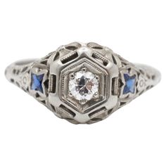 an antique diamond and blue sapphire ring with filigrees on the sides, in white gold