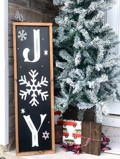 a christmas tree next to a sign that says joy with snowflakes on it