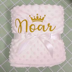 a baby blanket with a crown on it and the word moar written in gold