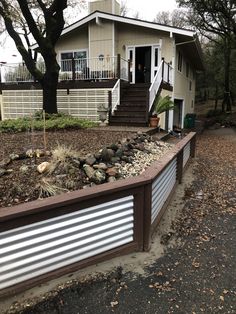 a house that is next to a tree and some rocks on the ground in front of it