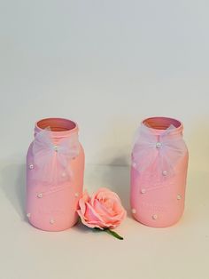 two pink mason jars with pearls and a single rose on the bottom one is empty