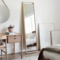 a bedroom with a bed, desk and mirror