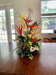 a wooden table topped with a vase filled with different types of flowers on top of it