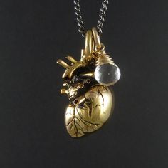 My Anatomical Heart necklace, beautifully detailed, cast in solid bronze and plated in 24 karat gold. A crystal clear quartz, beautifully faceted and skillfully wrapped in sterling silver gold filled wire. Sometimes I really wish I was a better photographer, to do this beauty the justice it deserves. The heart itself is as anatomically correct a heart as you'll find, lovingly detailed, meticulously crafted. Every artery and valve, every atrium and ventricle are captured in this pendant, and it h Unique Heart-shaped Gold Jewelry, Unique Gold Heart-shaped Jewelry, Unique Gold Heart Pendant Jewelry, Unique Gold Jewelry With Heart Charm, Heart-shaped Spiritual Brass Jewelry, Nickel Free Heart-shaped Brass Jewelry, Nickel Free Heart Shaped Brass Jewelry, Nickel Free Brass Heart-shaped Jewelry, Nickel-free Heart-shaped Brass Jewelry