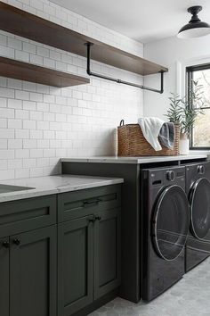 a washer and dryer in a kitchen with open shelving above the sink