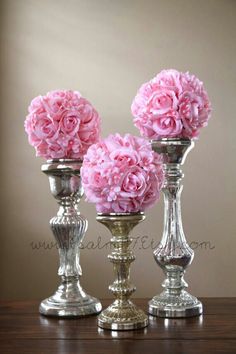 three silver vases with pink flowers in them