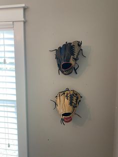 two baseball mitts mounted to the wall in a room with blinds on both sides