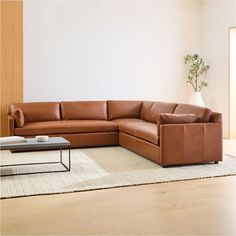 a living room with a sectional couch and coffee table on the floor in front of a white wall