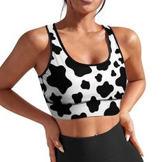 a woman wearing a black and white cow print sports bra with her hands on her hips