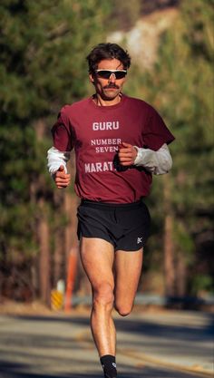 a man running down the road wearing a maroon shirt