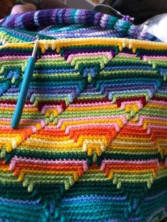 a crocheted blanket with a blue needle on it