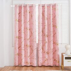 a pink curtain with gold foil paint on it in front of a white wall and wooden floor