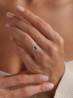 a woman's hand with a ring on her finger and a blue stone in the middle