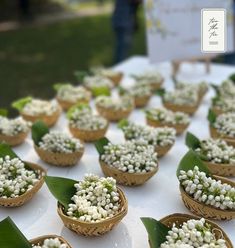 small baskets filled with white flowers sitting on top of a table covered in green leaves