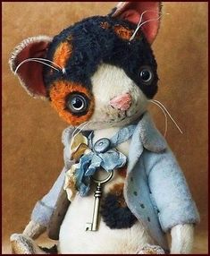 a stuffed animal cat with a key on it's chest and wearing a coat