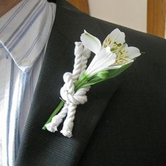 a boutonniere with white flowers is tied to a black suit blazer