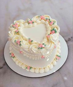 a heart shaped cake on a white plate with pink and green flowers in the shape of a heart