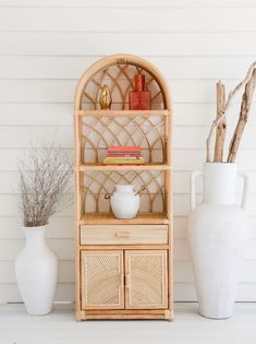 a white vase sitting on top of a wooden shelf next to a bamboo shelf unit