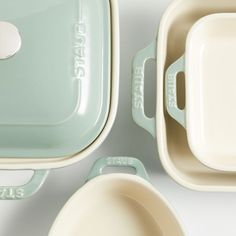 three dishes with lids and spoons sitting next to each other