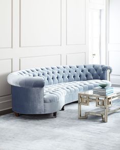 a blue couch sitting next to a table on top of a carpeted floor in front of a white wall