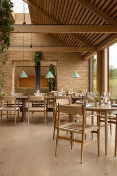 a restaurant with wooden tables and chairs in the middle of an open area that has large windows