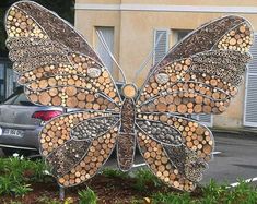 a metal butterfly sculpture sitting on top of a flower bed