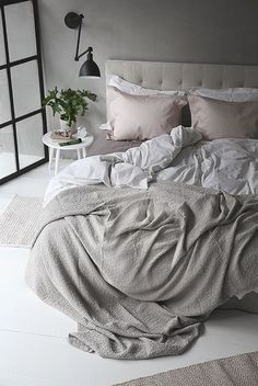 an unmade bed with pillows and blankets on it in a room that has white walls