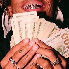 a man holding money in his hands and smiling at the camera while wearing a ring