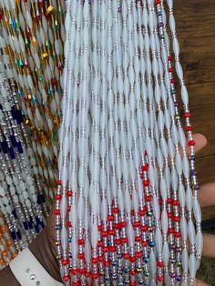 a person is holding some beads in their hand and they are all white with red accents