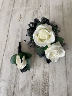 three white roses with green leaves on a wooden floor