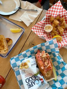 lobster sandwich and fries on the table at a restaurant with lemon wedges next to it