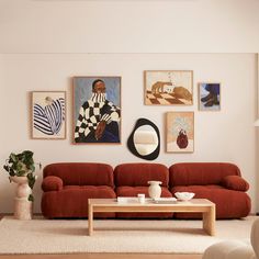 a living room with red couches and pictures on the wall above it, along with a coffee table