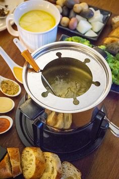 food is being prepared on a table with bread, soup and other foods in bowls